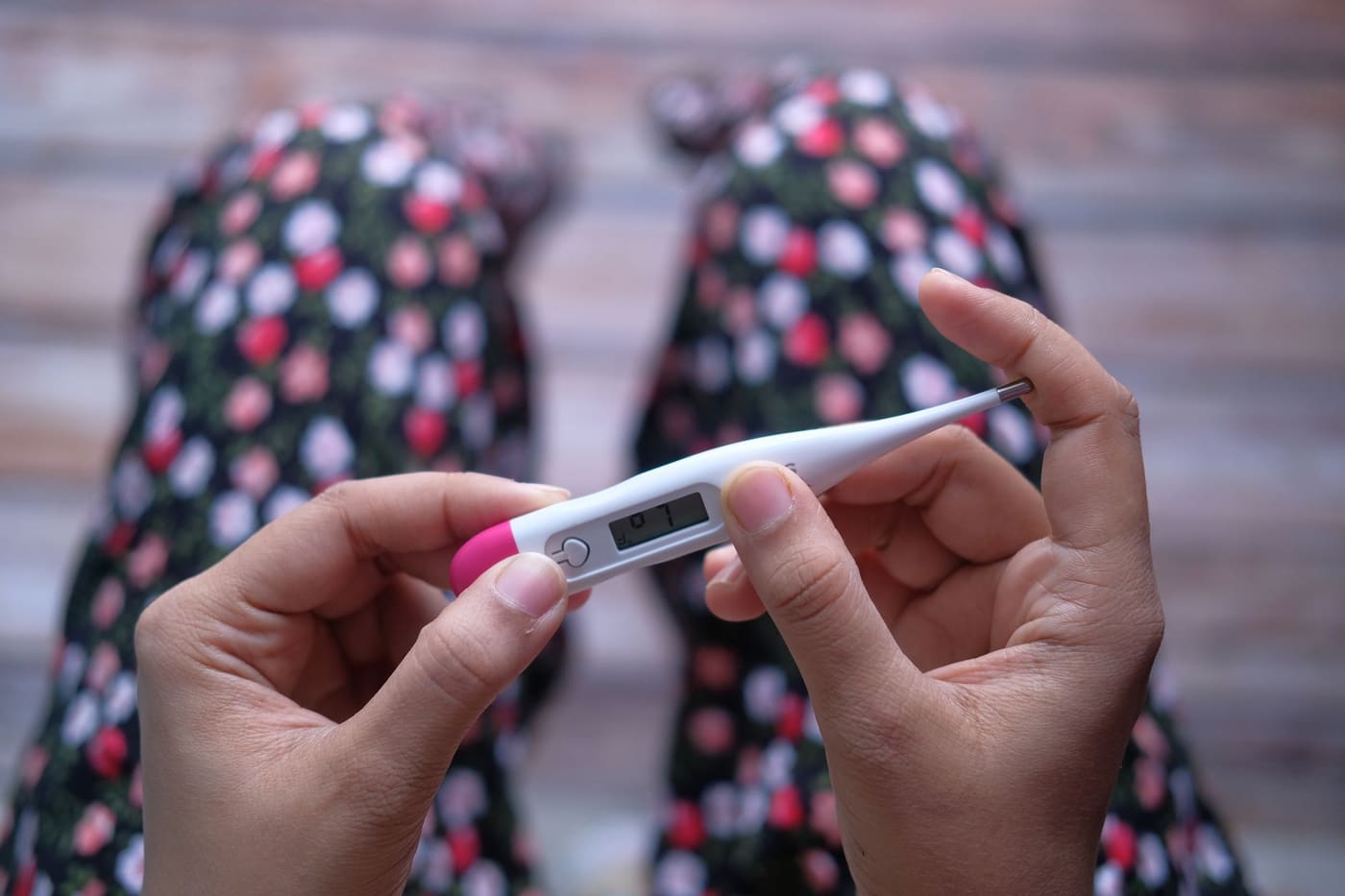 Hands holding a white digital thermometer with a pink tip